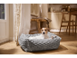 Dog in a grey pet bed in a cozy interior with wooden furniture.