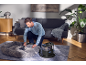 Man cleaning a pet bed with a textile cleaner in the living room.
