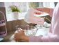 Person using a pink hand mixer to whisk ingredients in a glass bowl on a kitchen counter.