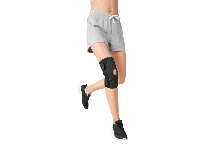 Woman in grey shorts and black knee brace running.