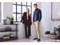 A man and woman pose in stylish casual outfits, the man in a shirt and trousers, the woman in a blazer and trousers.
