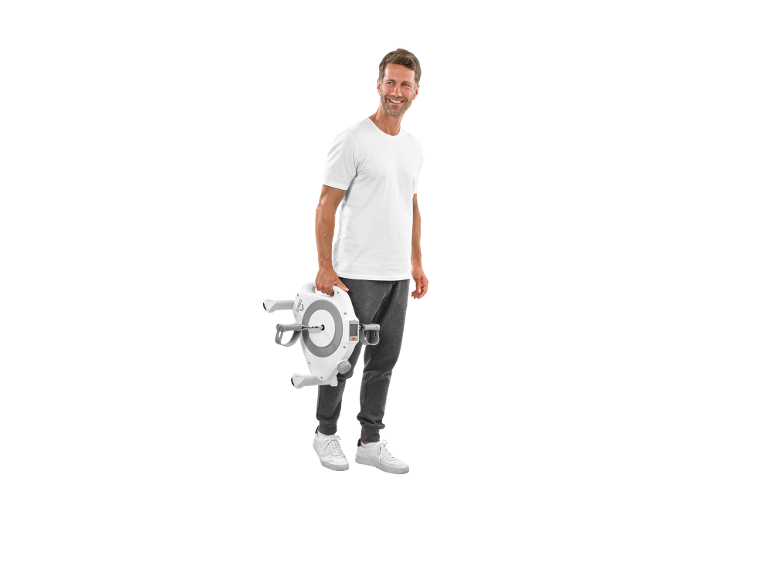 Man in white t-shirt and grey sweatpants holding a portable pedal exerciser.