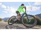 Man in neon jacket riding a mountain bike on a dirt road.