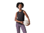 Woman in black tank top and purple leopard leggings, holding a fitness ball.