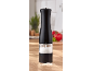 Black salt grinder with a clear base, filled with salt, on a wooden table.