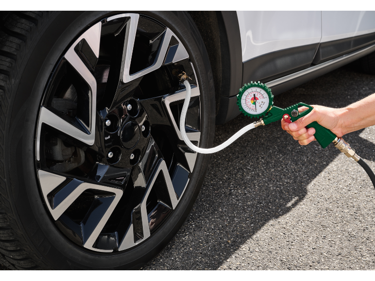 Tire inflator with pressure gauge connected to a car tire valve.