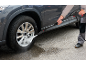 Man cleaning a dirty car wheel rim with a pressure washer.
