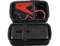 Black portable car jump starter with red clamps and cables in a case.