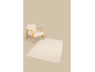 Beige armchair with a wooden frame and a light rug on the floor.