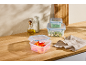 Plastic food containers, oil bottles, and a pitcher on a wooden table.