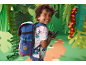Smiling boy with blue backpack and patterned t-shirt in a jungle setting.