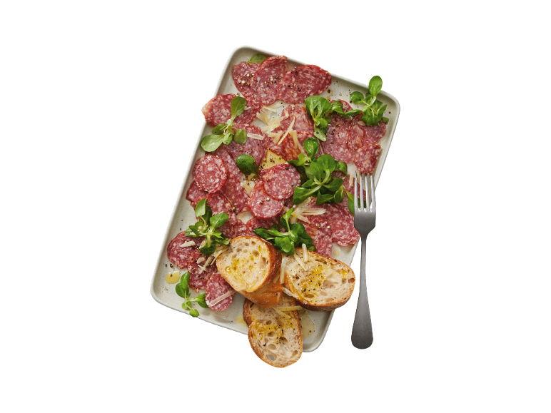 Plate of salami, cheese, lettuce, and bread with olive oil.