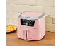 Pink air fryer with fries on a wooden table.