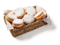 Powdered sugar doughnuts in a wicker basket with a cloth.