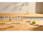 White wine glasses, some filled, with grapes and crackers on a wooden counter.