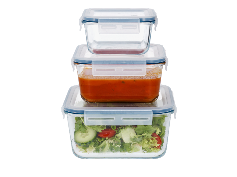 Stacked glass food storage containers, one with tomato sauce, another with salad.