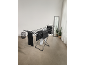 Black clothes drying rack with dark laundry in a bright room.