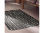 Grey striped bath mat on a tiled floor with folded towels in the background.