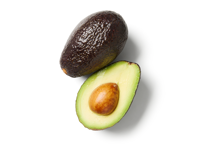 Whole avocado and half avocado with pit on a white background.