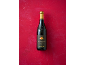 A bottle of Barbera d'Asti Superiore 2018 red wine on a red background.