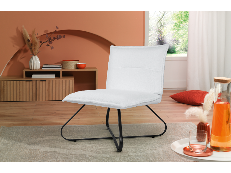 White armchair with black legs in a living room with earthy-toned decor.