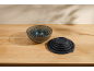 Set of nesting glass bowls with black lids on a wooden table.