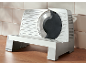 Silver-colored electric food slicer with a round blade, on a wooden table.