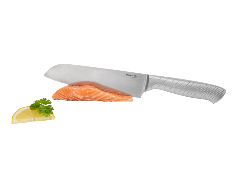 Kitchen knife slicing a salmon fillet with lemon and parsley.