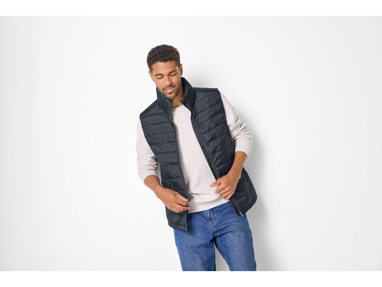 Man in black quilted vest, long-sleeved shirt, and blue jeans.