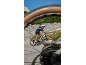 Man on an electric bike on a mountain road, shot through a bike wheel.