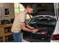 Man placing a trunk organizer with cleaning products into the car.