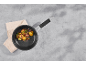 Sautéed potatoes and bacon in a frying pan on a kitchen towel, top view
