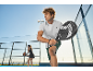 Man and woman playing padel on an outdoor court, man holding a padel racket.