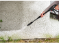 Person cleaning a wall with a pressure washer, removing green algae.