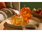 Two illuminated decorative pumpkins on a tray, with a cozy living room in the background.