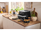 Air fryer on a kitchen counter with baking ingredients and fresh muffins.