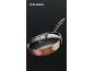 Copper-colored frying pan with a glass lid and metal handle on a dark background.