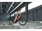 Man on black electric bicycle in a modern warehouse with floor markings.