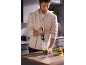 Man in kitchen making pesto with a hand blender.