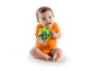 Smiling baby in an orange onesie, sitting and holding a frog rattle.