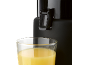 Close-up of a juicer dispensing orange juice into a glass.