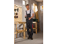 Man in work overalls holding a jigsaw in a workshop with tools and workbench.