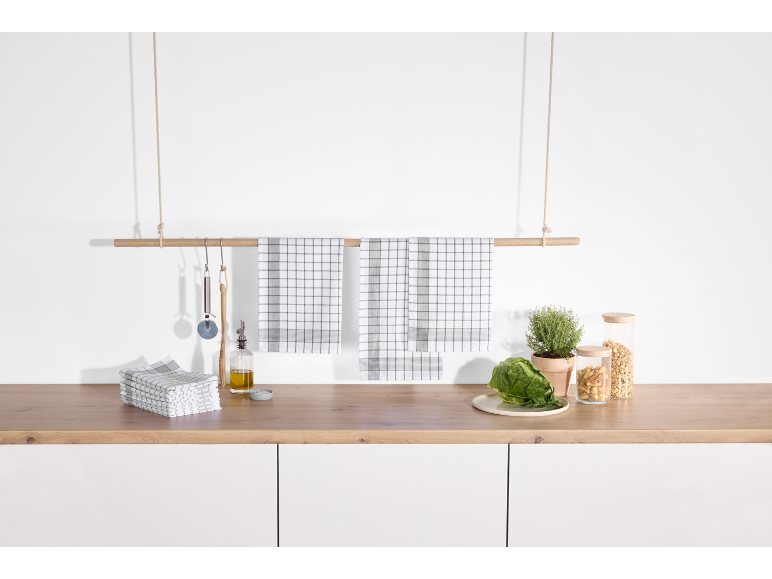 Black and white checkered kitchen towels hanging on a wooden bar above a kitchen counter.