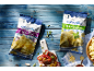 Two bags of chips, garlic and olive, and oregano, on a blue wooden table.