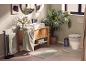 Modern bathroom with green towels, wooden cabinet, sink, and toilet, decorated with plants.