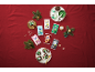 Colorful fondant packets and decorated cupcakes on a festive red cloth.