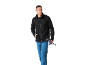 Man in black fleece jacket and blue trousers holding hiking poles.