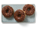 Three chocolate-glazed donuts with sprinkles on a grey platter.