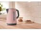 Pink kettle with grey details in a kitchen with a wooden countertop and white tiles.
