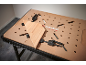 Workbench with a perforated top and clamps holding a wooden plank.